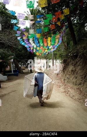 Fornitore di spiaggia che porta le sue sedie di amaca per vendere sulla spiaggia di Los Muertos vicino Sayulita, Nayarit, Messico. Foto Stock