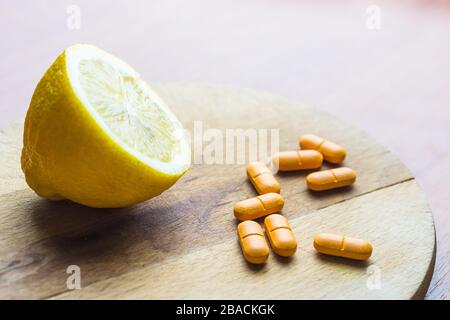 Pillole accanto ad un limone su una superficie di legno Foto Stock