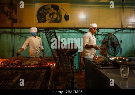 Il personale cucina a fiamme libere presso un ristorante di pesce alla griglia, ho Chi Minh City, Vietnam Foto Stock