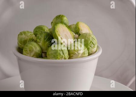 Piccola ciotola bianca piena di germogli di bruxelles lavati. Foto Stock