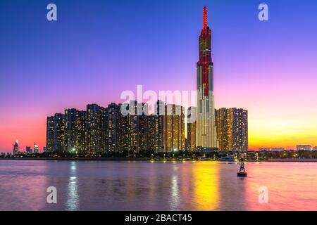 Il colorato paesaggio del tramonto in un'area urbana lungo il fiume con grattacieli che mostrano lo sviluppo più economico nella città di ho Chi Minh, in Vietnam Foto Stock