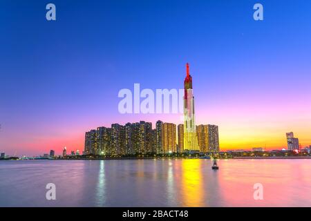 Il colorato paesaggio del tramonto in un'area urbana lungo il fiume con grattacieli che mostrano lo sviluppo più economico nella città di ho Chi Minh, in Vietnam Foto Stock