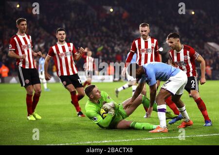 Raheem Sterling della città di Manchester (a destra) cerca di ottenere il pallone dal portiere Unito di Sheffield Dean Henderson dopo aver salvato una pena Foto Stock