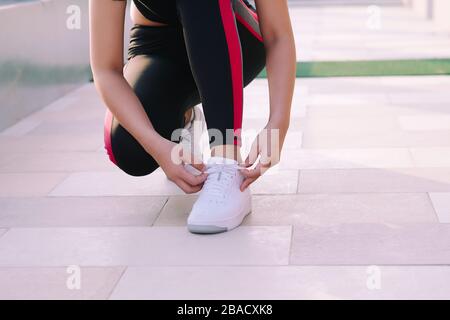 Primo piano di giovane donna legando i suoi lacci prima di una corsa. Foto Stock