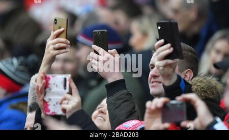 I fan tengono i loro telefoni cellulari negli appositi supporti Foto Stock