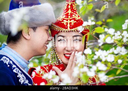 Ritratto di coppia felice in costumi kazako in fioritura primaverile apple giardino di Almaty in Kazakistan e in Asia centrale Foto Stock