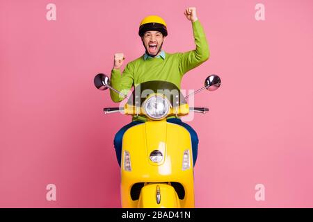 Ritratto del suo bello attraente fortunato eccitato positivo allegro ragazzo allegro cavalcando ciclomotore gioendo festeggiando avendo divertimento isolato su rosa Foto Stock