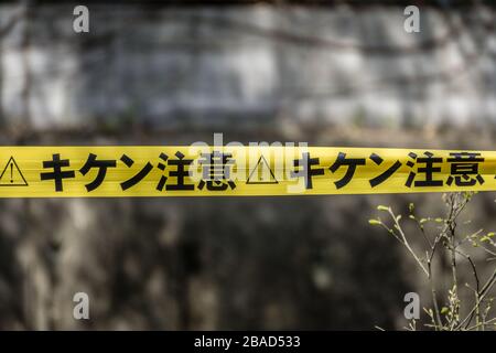 Nastro di avvertimento giallo e nero giapponese. La scrittura sul nastro si traduce in 'avvertenza' o 'attenzione'. Foto Stock