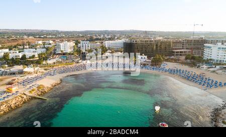 Vista aerea dall'alto della spiaggia di Vathia Gonia, Ayia Napa, Famagosta, Cipro. L'attrazione turistica punto di riferimento baia rocciosa all'alba con sabbia dorata, sole Foto Stock