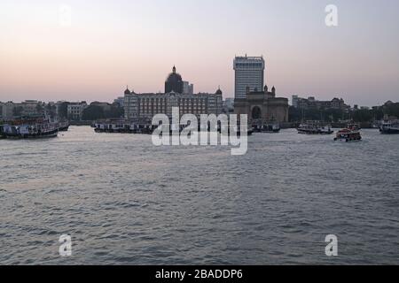 Taj Mahal Hotel, Gateway of India e barche turistiche in acqua del Mar Arabico al tramonto a Mumbai, India Foto Stock