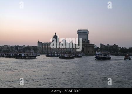 Taj Mahal Hotel, Gateway of India e barche turistiche in acqua del Mar Arabico al tramonto a Mumbai, India Foto Stock