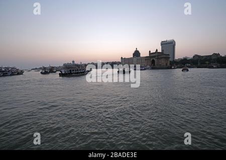 Taj Mahal Hotel, Gateway of India e barche turistiche in acqua del Mar Arabico al tramonto a Mumbai, India Foto Stock