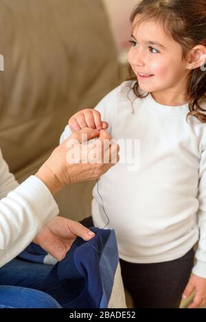 Nonna insegna la sua nipote a Mend Clothes. Il bambino che è homeschooled dovuto la scuola ha shut giù durante la Pandemic di Covid-19. Foto Stock