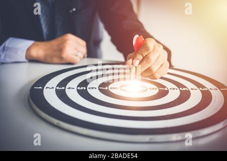 L'uomo di affari che tiene i colpi di dart Bullseye è un obiettivo e un obiettivo del commercio che commercializza come concetto. Foto Stock