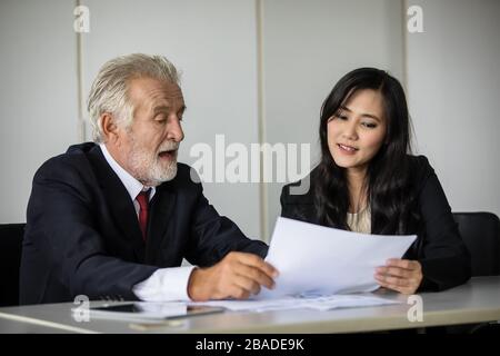 Imprenditori documenti di contenimento per i business partner per discutere e condividere idee ad una riunione di affari e le donne sorridendo felice per il lavoro Foto Stock