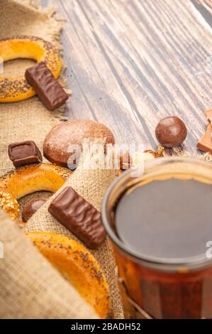 Un bicchiere di tè, bagel, pan di zenzero e cioccolato su uno sfondo di legno. Primo piano Foto Stock