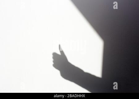 silhouette shadow mano facendo tumbi su parete bianca, isolato in casa Foto Stock