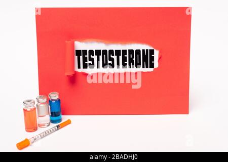 Testosterone scritta in buco di carta rossa, siringa e vasi di farmaci ormonali su sfondo bianco Foto Stock