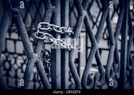 Catena su un cancello metallico. I cancelli massicci sono chiusi dall'interno con un lucchetto con una catena robusta. Vista laterale. Messa a fuoco selettiva.primo piano. Senza peopl Foto Stock