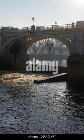 Luce del sole che passa attraverso l'arco di Richmond Lock con le barriere giù e acque turbolente, Richmond-upon-Thames, Surrey Foto Stock