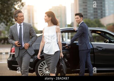 Gente d'affari cinese fiduciosa che esce dall'automobile Foto Stock