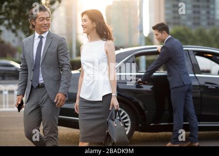 Gente d'affari cinese fiduciosa che esce dall'automobile Foto Stock