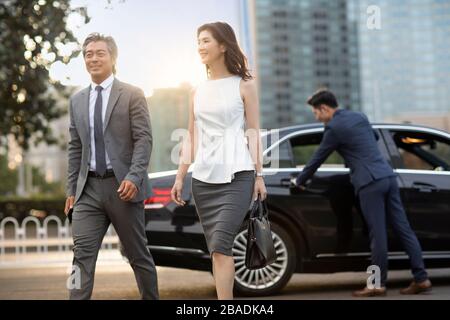 Gente d'affari cinese fiduciosa che esce dall'automobile Foto Stock