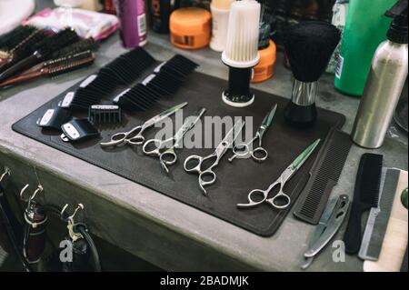 Utensili per tagliare i capelli con forbici, spazzola per capelli e pettine sul bancone nel bariletto Foto Stock