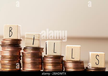 Blocchi di legno con la parola bollette e mucchio di monete, soldi scalini pagamento delle tasse e del debito allo Stato. Concetto di crisi finanziaria e. Foto Stock