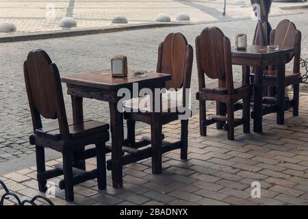 Tavoli e sedie in legno in un caffè di strada in stile retrò senza persone Foto Stock