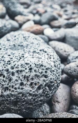 Chiudere l immagine di una roccia vulcanica su una spiaggia, il fuoco selettivo, tonificazione del colore applicato. Foto Stock