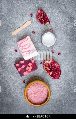 Vista dall'alto di saponi di frutta e cosmetici di melograno organici su sfondo grigio di pietra. Foto Stock