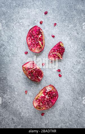 Vista dall'alto della frutta di melograno strappata su sfondo di pietra grigia. Foto Stock