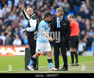 Sergio Aguero (centro) di Manchester City riceve un pat in testa dal suo manager Roberto Mancini dopo essere stato sostituito Foto Stock