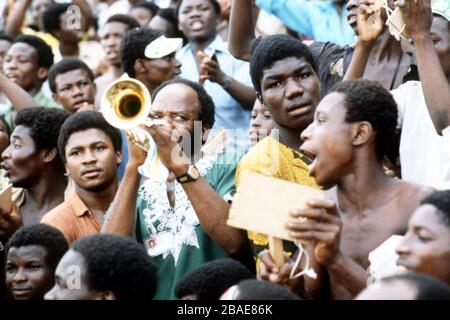 Un fan nigeriano suona una tromba per radunare i suoi vicini tra la folla Foto Stock