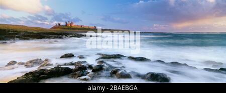 Dunstanburgh Castle attraverso Craster Beach, Northumberland, Inghilterra Foto Stock