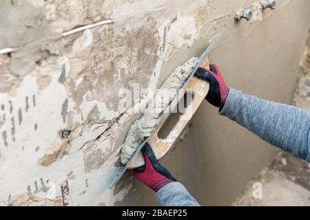 allineamento delle pareti - operaio edile che lavora con cazzuola e intonaco Foto Stock