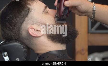 Barbiere giovane regolabarba del cliente maschio Foto Stock