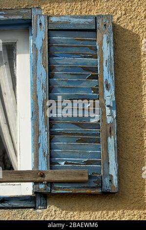 Vecchie persiane finestra su una casa a Cipro, con vernice blu che si distacca. Foto Stock