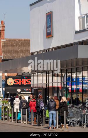 Gli acquirenti si accodano al di fuori del superstore di Aldi a Westcliff on Sea durante il blocco per l'epidemia di virus pandemico del Coronavirus COVID-19. Alcuni si avvicinano Foto Stock