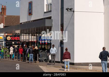 Gli acquirenti si accodano al di fuori del superstore di Aldi a Westcliff on Sea durante il blocco per l'epidemia di virus pandemico del Coronavirus COVID-19. Alcuni si avvicinano Foto Stock