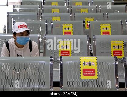 Bangkok, Thailandia. 27 marzo 2020. Un passeggero guarda su mentre siede accanto alle sedie con gli adesivi per mantenere le distanze sociali per fermare la diffusione del Coronavirus Covid-19 in un terminal degli autobus a Bangkok. A livello globale, il virus ha ora infettato più di 532,670 persone e ha ucciso almeno 24,092 persone. Credit: Urdee Image/ZUMA Wire/Alamy Live News Foto Stock