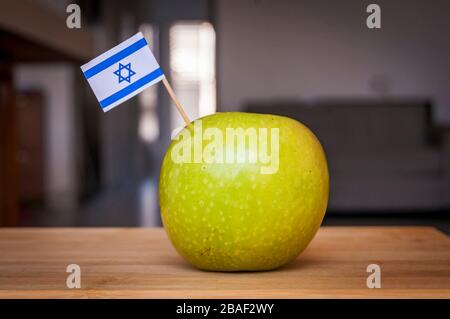 Granny Smith mela verde cresciuta in Israele con una piccola bandiera israeliana. Frutta fatta in Israele, immagine di concetto di frutta israeliana. Capodanno ebraico Rosh Hashana Foto Stock