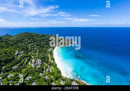 Vista aerea panoramica della baia di Anse Petite con sabbia bianca, mare turchese, oceano blu e lussureggiante promontorio boscoso, Mahe, Seychelles Foto Stock