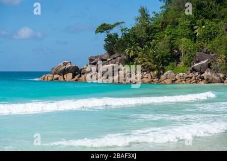 Vista panoramica aerea con drone della costa di Anse Georgette con colline verdi, mare turchese e blu profondo dell'Oceano Indiano, Praslin, Seychelles Foto Stock