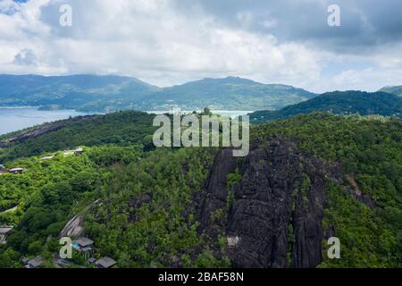 Vista panoramica aerea con drone della lussureggiante catena montuosa verde e cielo nuvoloso sull'interno dell'isola di Mahe, Seychelles Foto Stock