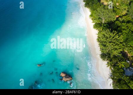 Vista aerea dall'alto verso il basso della spiaggia di Anse Lazio con sabbia bianca, acque turchesi e nuotatori, Praslin, Seychelles Foto Stock