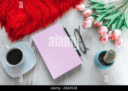 Matita e un taccuino rosa su tavola di legno bianco. Vista dall'alto, concetto di simulazione Foto Stock