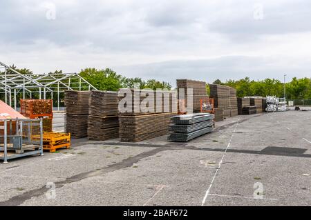 Costruzione di stand di una fiera regionale, costruzione di tende, pali di legno e tavole di legno per il pavimento della tenda sulla pila, tende sullo sfondo, alu Foto Stock