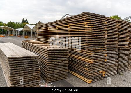 Costruzione di stand di una fiera regionale, costruzione di tende, pali di legno e tavole di legno per il pavimento della tenda sulla pila, tende sullo sfondo, alu Foto Stock